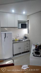 a kitchen with white cabinets and a white refrigerator at Flat com Sacada - Região Ibirapuera próximo vários Hospitais e UNIFESP in Sao Paulo