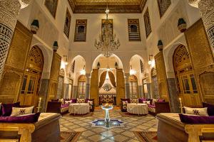 Habitación grande con mesas, sillas y lámpara de araña. en Riad Marjana suites & Spa, en Fez