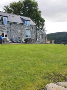 a person standing in front of a stone house at 3 Bedroom Barn Conversion -Garden View - Ty Cerrig Barn in Corwen