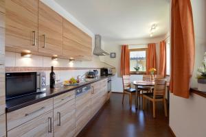 a kitchen with wooden cabinets and a table with a dining room at Appartement Angelika in Schwendau