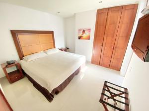 a bedroom with a large bed and a wooden door at Atlantic Garden Hotel in Barranquilla
