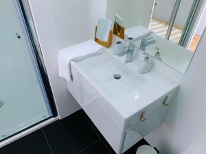 bagno con lavandino bianco e specchio di L'Azor Suites - Bleuté a Ponta Delgada