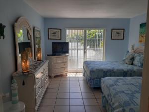 a bedroom with two beds and a dresser with a television at Turtle Crawl Inn - Longboat Key in Longboat Key