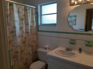 een badkamer met een wastafel, een toilet en een spiegel bij Turtle Crawl Inn - Longboat Key in Longboat Key