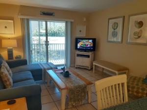 a living room with a couch and a tv at Turtle Crawl Inn - Longboat Key in Longboat Key
