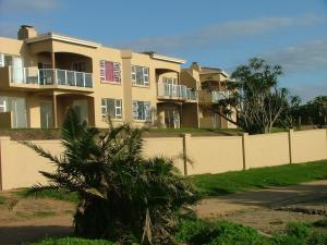 a building with a fence and a palm tree in front of it at 3 Marina Palms, Woodgrange-on-sea in Hibberdene
