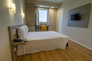 a hotel room with a large white bed and a television at Transamerica FIT Primavera do Leste in Primavera do Leste