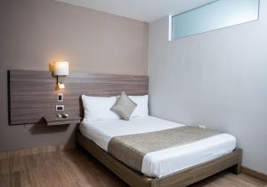 a bedroom with a bed with a wooden headboard at Hotel Betania in Santa Marta