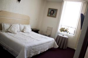 a bedroom with a white bed and a window at HOTEL ROMO in Ciudad Hidalgo