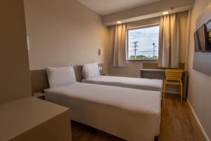 a hotel room with two beds and a window at Transamerica FIT Primavera do Leste in Primavera do Leste +19 photos