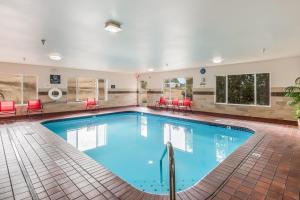 - une grande piscine dans une chambre d'hôtel dotée de chaises et de tables rouges dans l'établissement Red Lion Inn & Suites at Olympic National Park, à Sequim