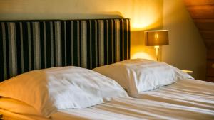 1 cama con almohadas blancas y cabecero a rayas en Ungru Guesthouse, en Suuresadama
