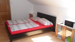 a small bedroom with a bed with red sheets and pillows at Apartman Vilo in Veľký Meder