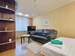 a living room with a leather couch and a television at Apartament on Gorkogo 26 in Bobruisk