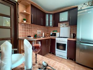 a kitchen with brown cabinets and a glass of wine at Apartament on Gorkogo 26 in Bobruisk
