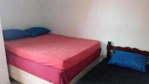 um pequeno quarto com uma cama com lençóis vermelhos e azuis em Casa temporada Itanhaem em Itanhaém