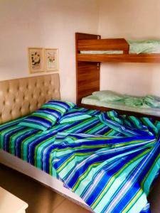 a bed with a colorful striped comforter in a bedroom at Hotel Villa De Carli Beach in Rio Grande