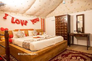 a bedroom with a bed with a love sign on the wall at Sky Desert Safari & Spa in Sām