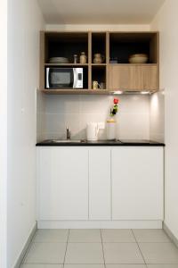 kuchnia z białymi szafkami i kuchenką mikrofalową w obiekcie °Le métropole° Check in H24/wifi w mieście Lyon