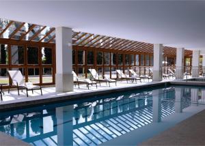 a swimming pool with chairs and a building at Nosso Flat Pedra Azul - Condomínio Vista Azul in Domingos Martins