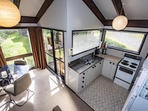 uma cozinha com grandes janelas e uma mesa e cadeiras em Foyle Street Ski Retreat - Ohakune Holiday Home em Ohakune