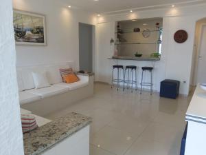 a white living room with a white couch and bar at CONDOMINIO GERIBA APART HOTEL APTO 116 in Búzios