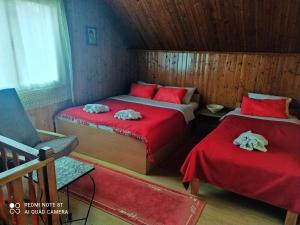 a bedroom with two beds with red sheets and a chair at Sweet dreams in Zaječar