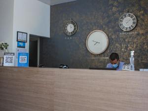a man wearing a mask behind a counter with a clock at Hotel Quinto Nivel in San José del Guaviare
