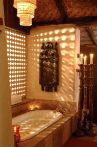 a bath tub in a room with lights on the wall at Mahua Kothi Bandhavgarh - A Taj Safari Lodge in Tāla