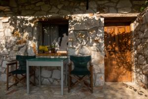 un tavolo e sedie di fronte a un muro di pietra di Filoxenia - The Place of Experience a Himare