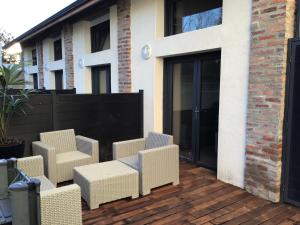 un patio con sillas de mimbre en una terraza de madera en Les spas de la Chartreuse en Tarbes