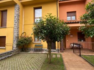 ein gelbes Gebäude mit einem Baum davor in der Unterkunft Alojamiento el Dorado in Llanes