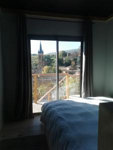 a bedroom with a bed and a large window at L'ABRI du château SPA et détente in Jarnioux