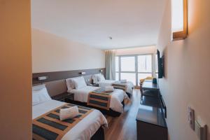 une chambre d'hôtel avec quatre lits et un canapé dans l'établissement SEC Hotel, à Mar del Plata