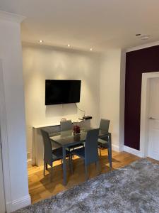 a dining room with a table and chairs and a television at Cheerful One bedroom cottage with parking space. in Glasgow