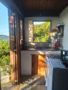 a kitchen with a window and a stove top oven at Chalé de Pedras no Pontal do Atalaia in Arraial do Cabo