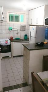 cocina con electrodomésticos blancos y suelo de baldosa blanca en Apartamento Taperapuã Praia Vilage, en Porto Seguro