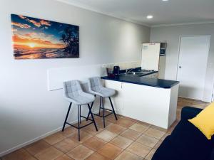 una cocina con 2 taburetes y una barra con fregadero en Cottage Park Thermal Motel en Tauranga