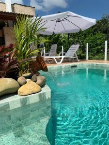 een zwembad met 2 stoelen en een parasol bij House Flat Cacupé em Florianópolis in Florianópolis