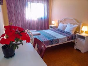 un dormitorio pequeño con una cama con flores rojas. en Friends in Braga - Charming Bedrooms in the Historic Center en Braga