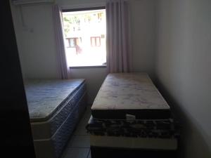 two beds sitting in a room with a window at APARTAMENTO 1 QUARTO EM PORTO SEGURo in Porto Seguro