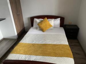 Una cama con manta amarilla y almohadas. en Hospedaje Casa Bachué, en Chía