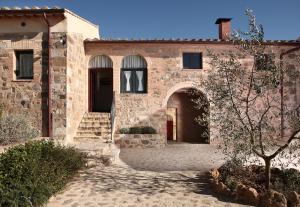 ein altes Steingebäude mit einem Torbogen und einem Innenhof in der Unterkunft Agriturismo Il Poggione in Montalcino