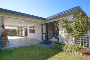 a home with a patio and a yard at Sunny Warren in Wanaka in Wanaka