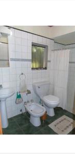 a white bathroom with a toilet and a sink at Jardín de Naipí in Puerto Iguazú