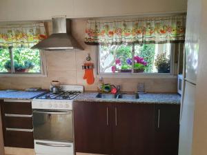 a kitchen with a stove and a sink and two windows at Casa Golfo Nuevo in Puerto Madryn