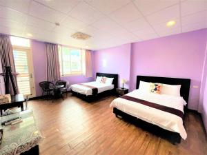 a bedroom with two beds and a purple wall at 台東新港民宿 in Chenggong +7 photos