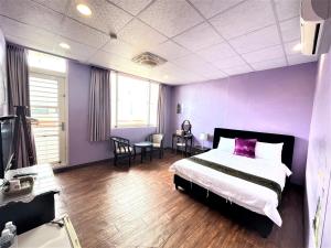 een slaapkamer met paarse muren en een bed en een tafel bij 台東新港民宿 in Chenggong