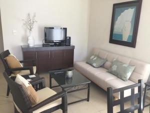 ein Wohnzimmer mit Sofa, Sesseln und Fernseher in der Unterkunft Acapulco, Departamento PB en Marina Diamante in Acapulco