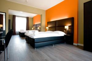 a bedroom with two beds and an orange wall at Hotel Roermond Next Door in Roermond